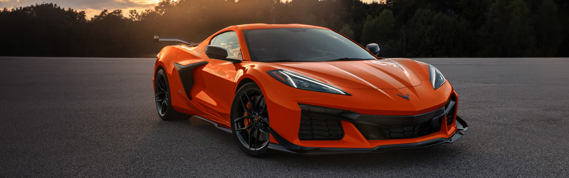 2026 Chevrolet Corvette Z06 performance coupe in orange with a bold front grille, sleek LED headlights, and track-ready styling at sunset.